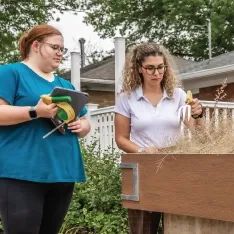 Two women working conducting an assessment outdoors next to a raised planter.